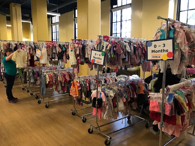 Racks of children's clothing for sale, organized by size
