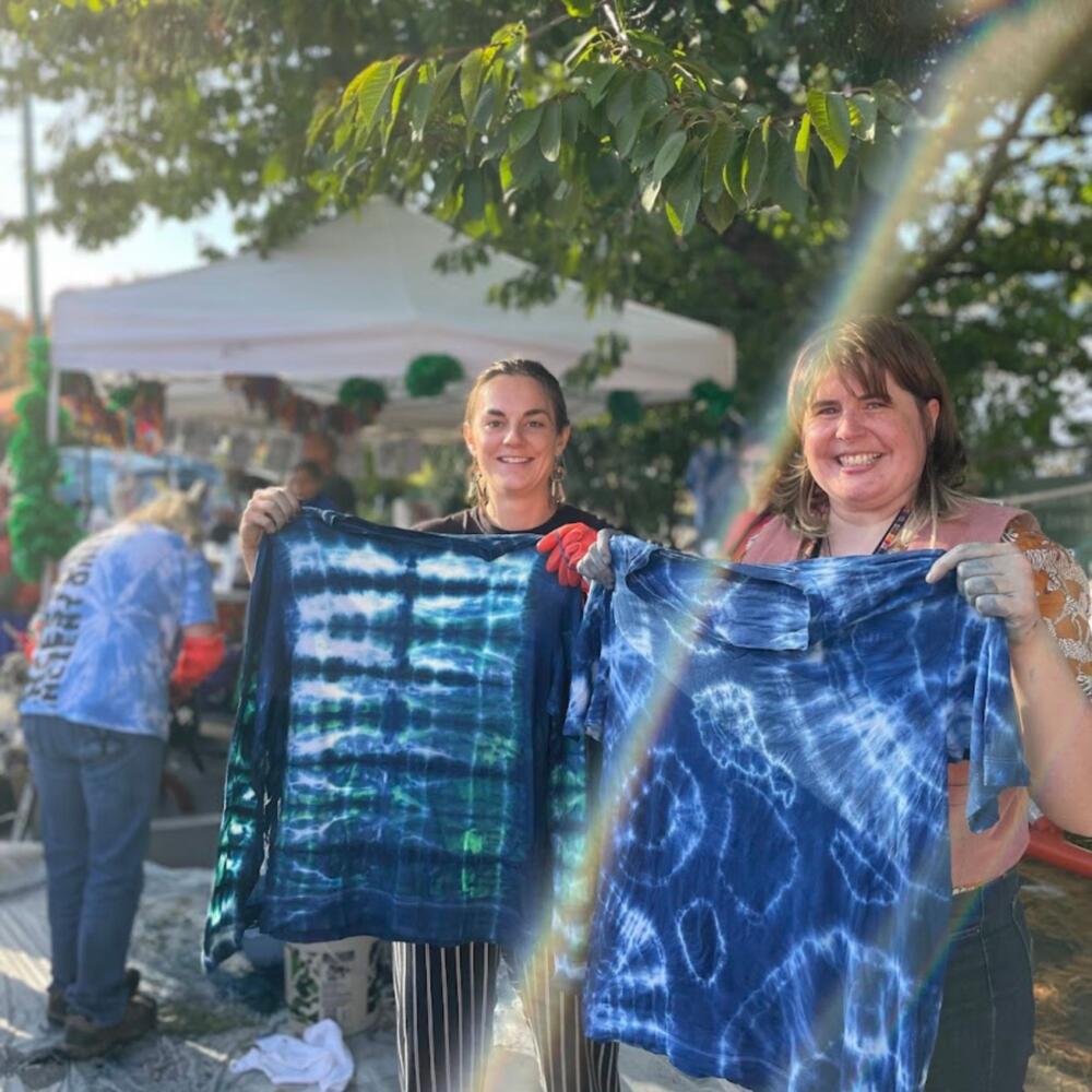 Two community members hold up their indigo dyed tshirts